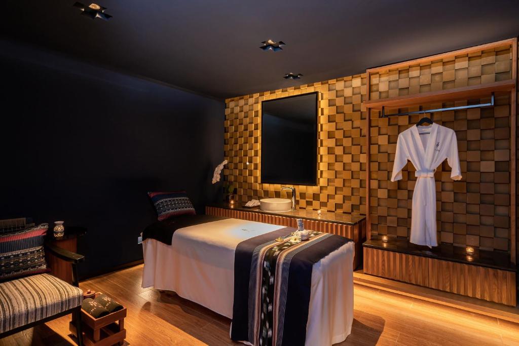 A warmly lit bedroom with a single bed, lounge chair and open wardrobe wall.