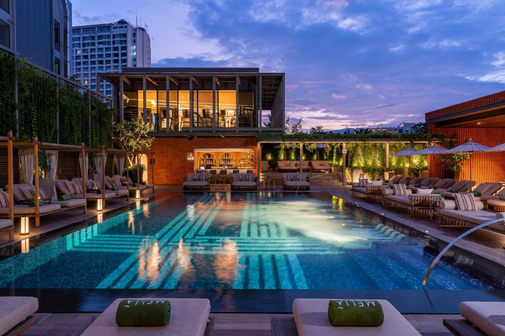 An atmospheric evening pool scene with illuminated cabanas and a poolside bar.