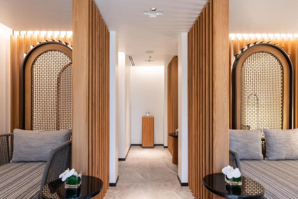 A bright hotel corridor framed by matching woven lounge chairs and small round tables.