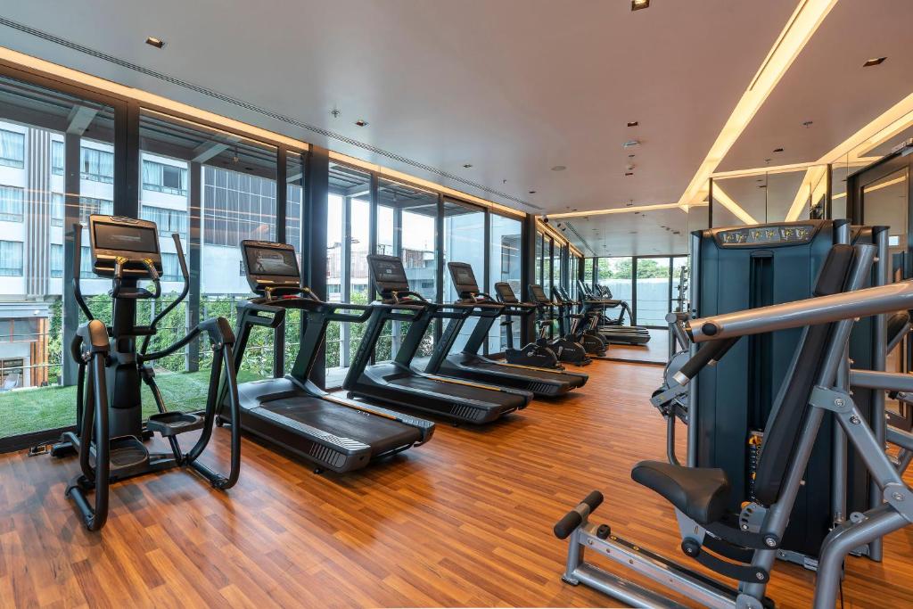 A bright, window-lined fitness room with cardio machines and a strength station.