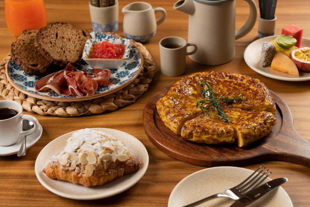 A styled breakfast spread with pastries, bread, fruit and a large baked egg dish.
