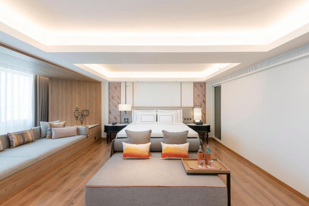 A bedroom with a large bed and a deep upholstered sofa facing a styled coffee table.