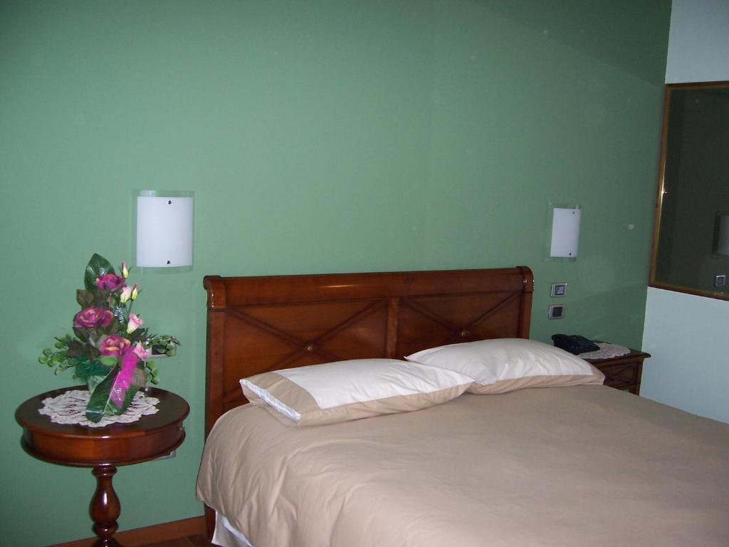 um quarto com uma cama e uma mesa com um vaso de flores em Locanda da Gerry em Castelcucco