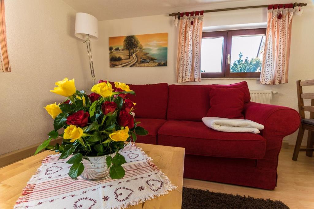 a living room with a red couch and a vase of flowers at Ferienhaus Rosalie in Altendorf