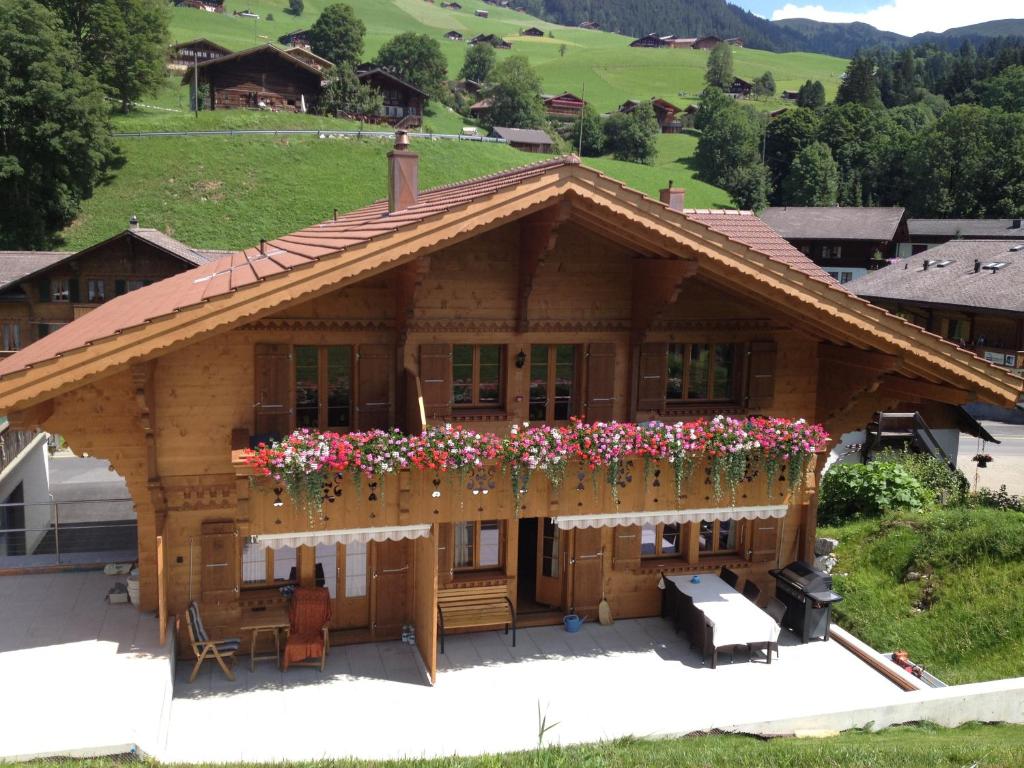 una casa de madera con flores en el balcón en B&B Panorama, en Gstaad