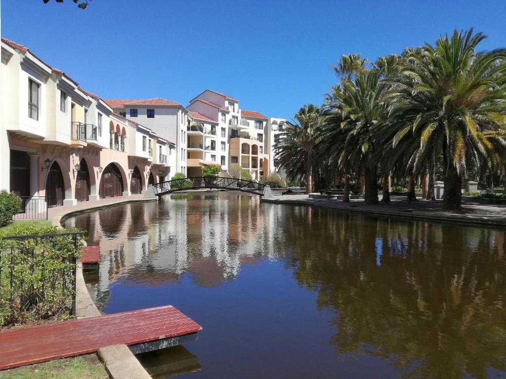 a canal in a city with palm trees and buildings at La Savina - The Island Club in Cape Town