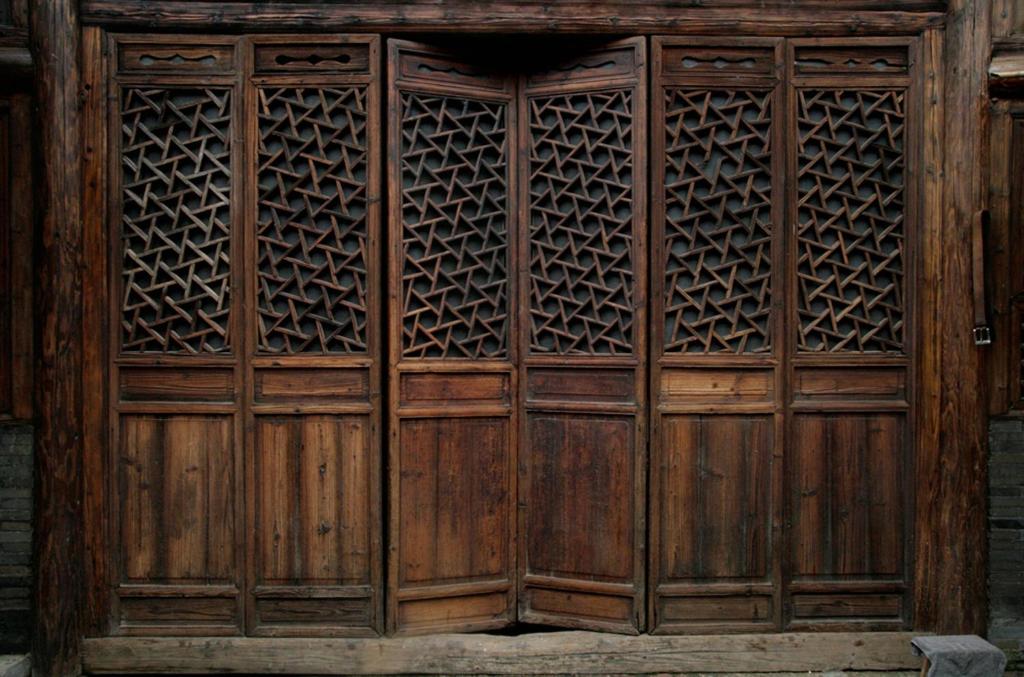 une vieille porte en bois avec des motifs sur elle dans l'établissement Laojia, a Qing dynasty house, à Xingping