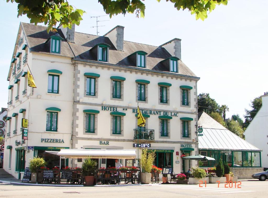 un grand bâtiment blanc avec un toit gris dans l'établissement Hôtel du Lac, à Huelgoat