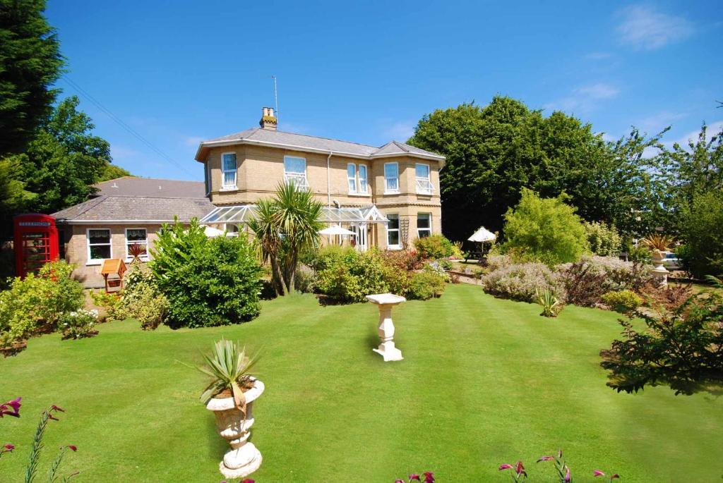 uma casa grande com um quintal verde com uma casa em Somerton Lodge em Shanklin