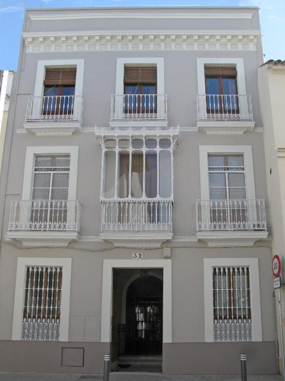 a white building with white windows and balconies at 19th Century Sevillian Apartment in Seville