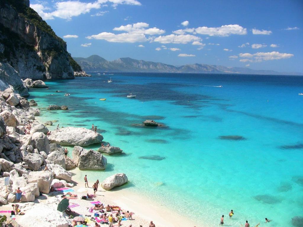 a group of people on a beach with blue water at Cala Gonone Cozy House Sea View in Cala Gonone