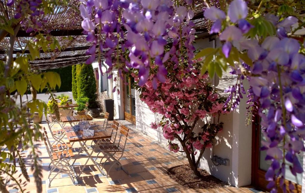un patio con mesas y flores púrpuras en Logis Hotel Le Nouvel, en Portes-lès-Valence