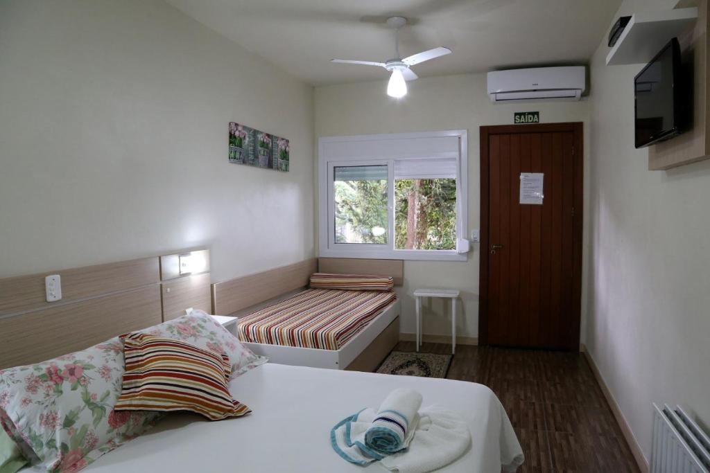 a small bedroom with a bed and a window at Pousada Caminho das Rosas - Gramado in Gramado