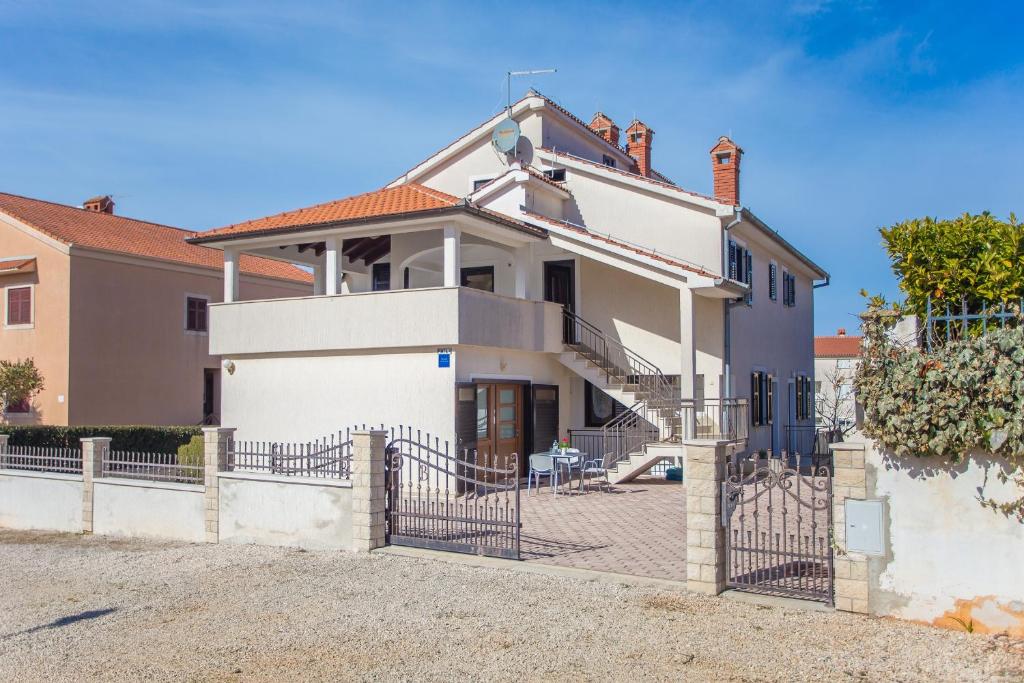 a white house with a fence in front of it at Apartments Punta in Poreč
