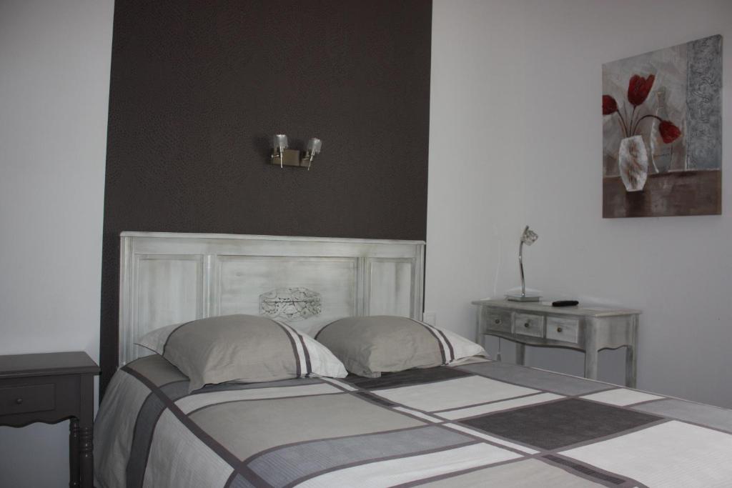 - une chambre avec un lit avec deux oreillers et une table dans l'établissement Hôtel le midi, à Montaigu-de-Quercy