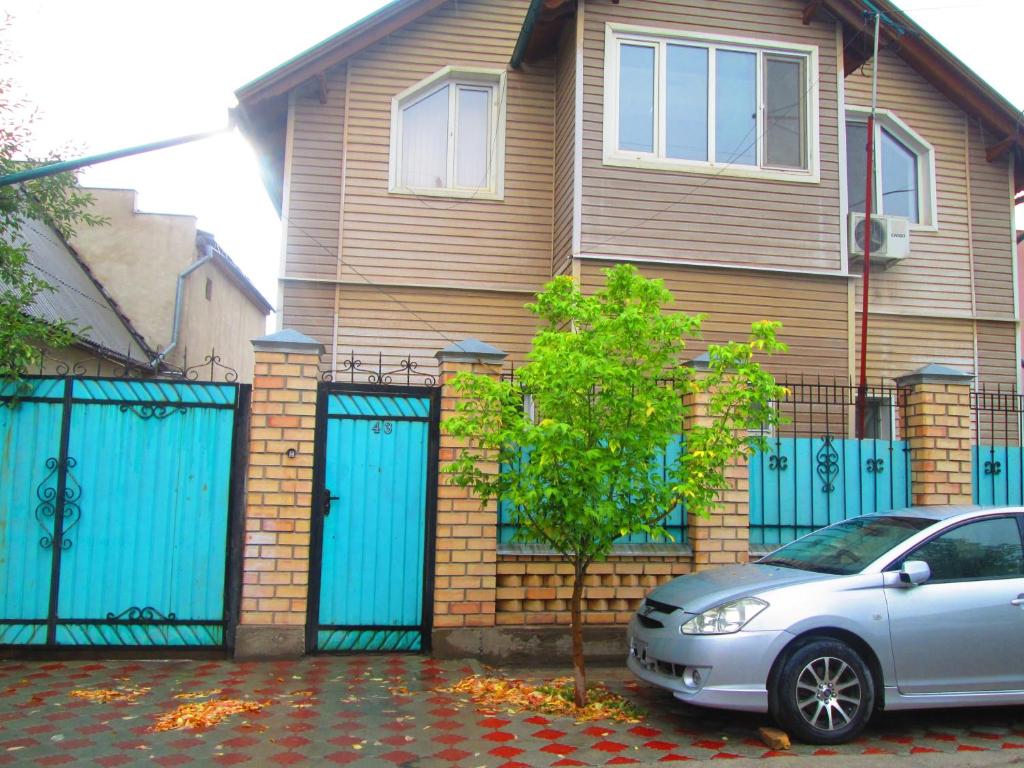 a car parked in front of a house with blue gates at Mukarama-Apa in Bishkek
