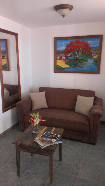 a living room with a brown couch and a table at Paradise Beach Hotel in Kingstown