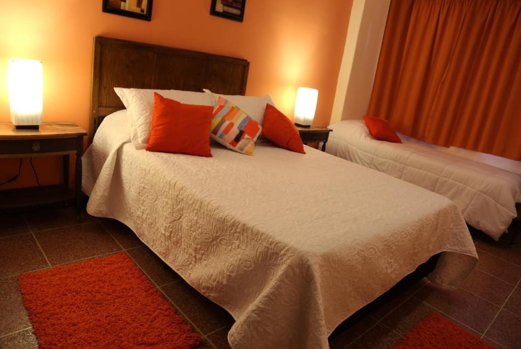 1 dormitorio con 2 camas y almohadas de color naranja y blanco en Hotel Bulevar, en Paysandú