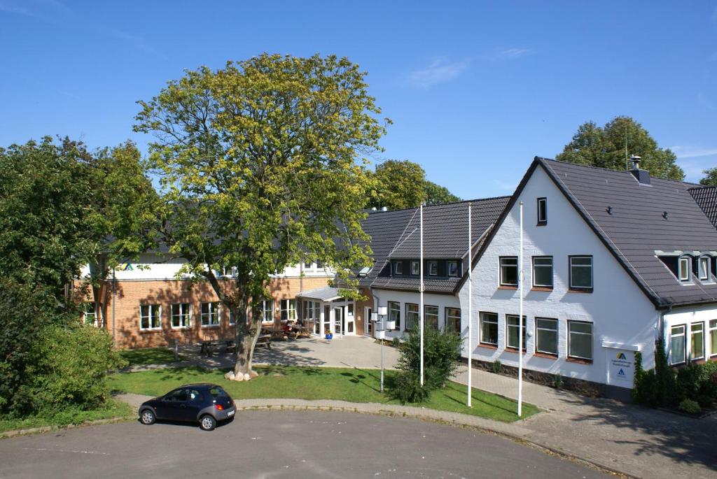 un coche aparcado en un aparcamiento frente a un edificio en Jugendherberge Friedrichstadt en Friedrichstadt