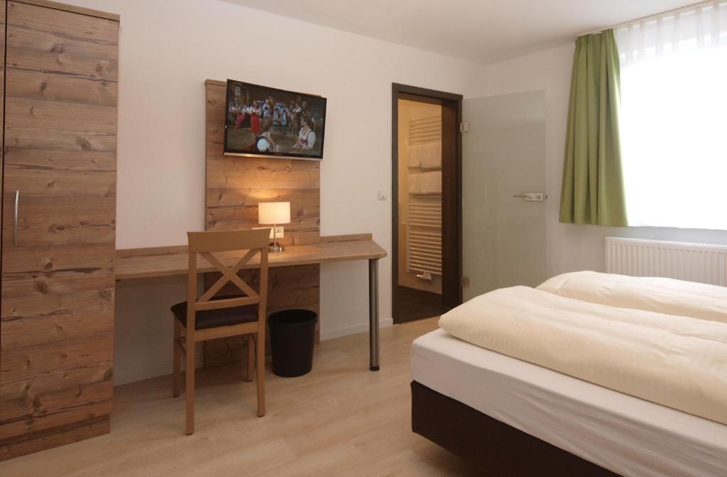 1 Schlafzimmer mit einem Bett und einem Schreibtisch sowie einem Bett der Marke sidx sidx sidx. in der Unterkunft Fränkischer Hof --- Hotel in Pegnitz --- Schlabecks Fränkischer Hof in Pegnitz