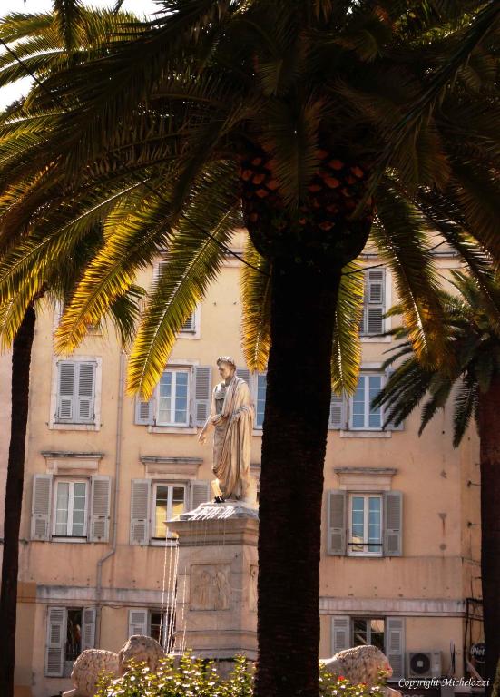 une statue devant un bâtiment planté de palmiers dans l'établissement Appartement coeur de ville, à Ajaccio
