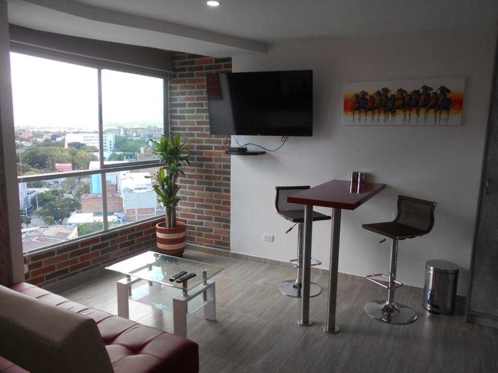 sala de estar con sofá, mesa y TV en All Inclusive Suites, en Medellín