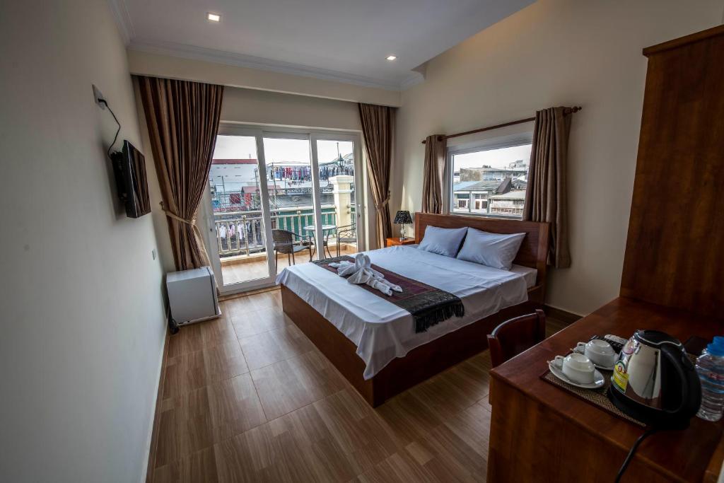 a hotel room with a bed and a balcony at Phnom Penh Le Vincent Hotel in Phnom Penh