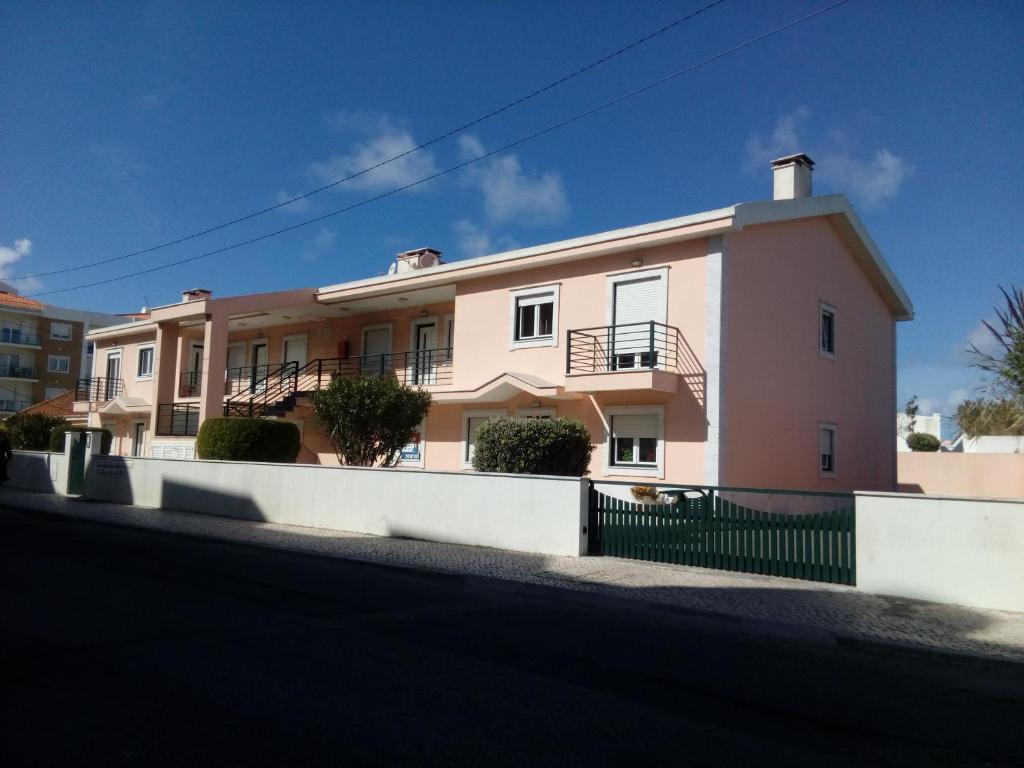 a pink building with a fence in front of it at Apartamento Porto de Areia in Peniche