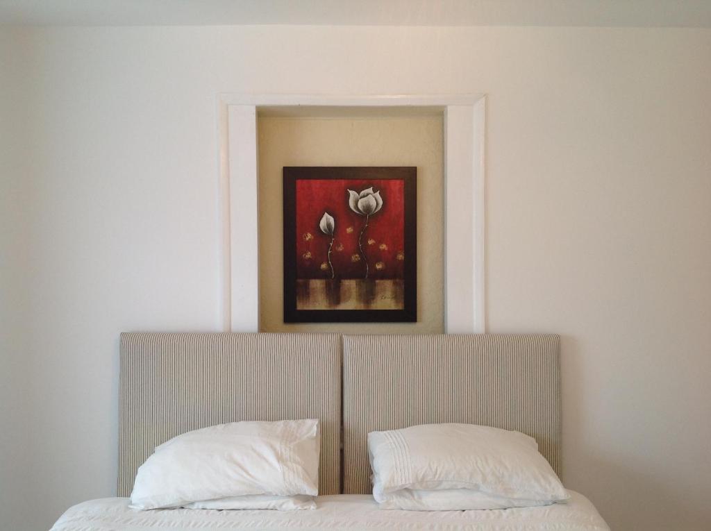 uma cama com duas almofadas e um quadro por cima em Repton Private Hotel em Romford