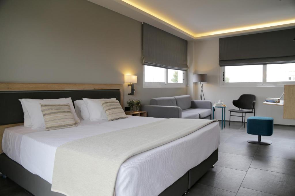 a bedroom with a large white bed and a living room at Palmyra Beach Hotel in Athens