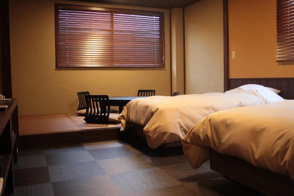 a bedroom with two beds and a table and a window at Tokiwa Ryokan in Nikko