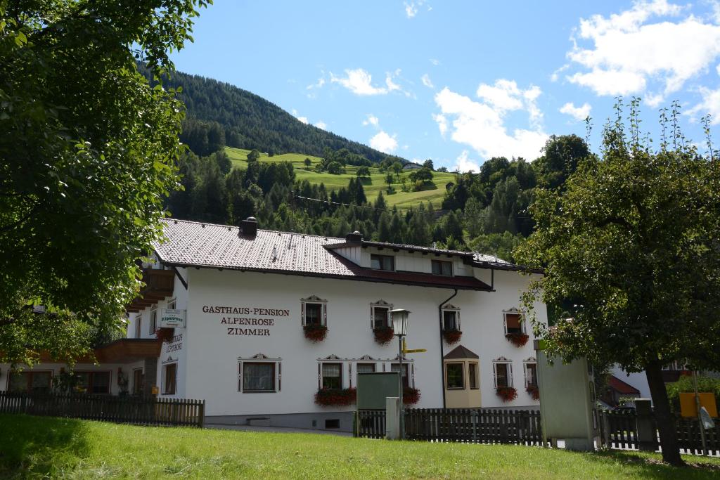 a white building with a mountain in the background at Gasthof Alpenrose in Imsterberg