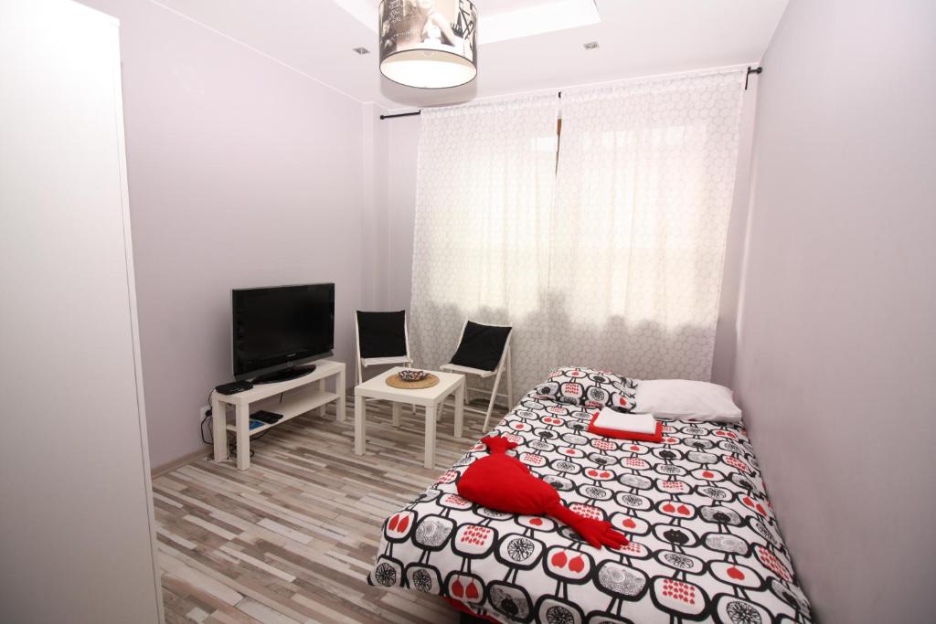 a small bedroom with a bed and a tv at Red Apartament in Łódź