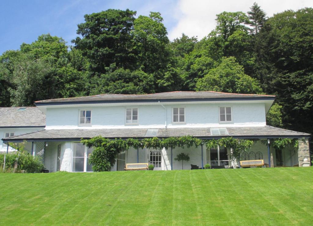 a white house with a large lawn in front of it at Plas Tan-Yr-Allt Historic Country House & Estate in Porthmadog