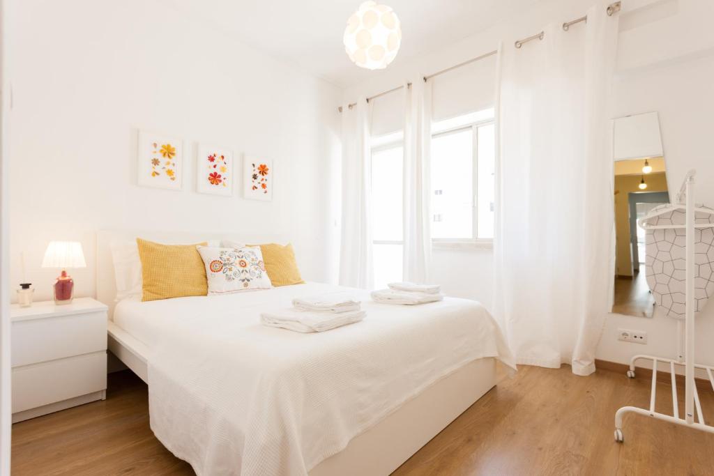 Habitación blanca con cama y ventana en FLH Marques Bright Apartment, en Lisboa