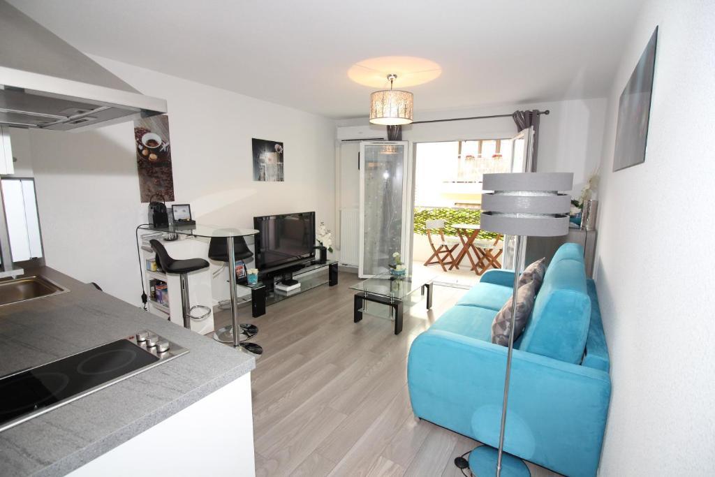 a living room with a blue couch and a kitchen at Villa Lympia in Nice