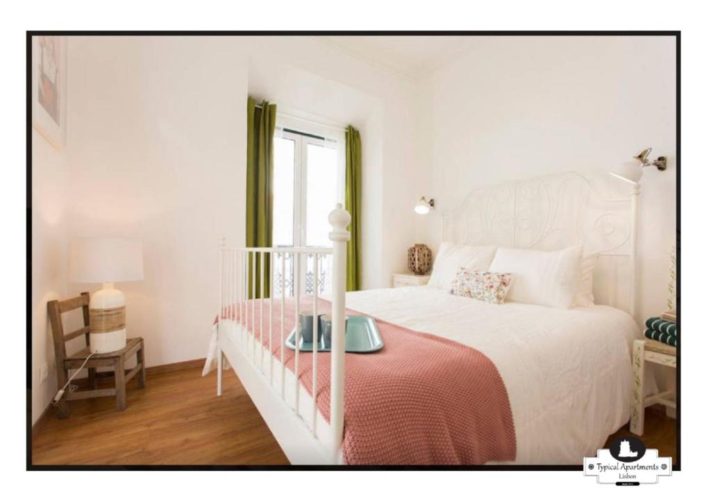 a bedroom with a white bed with a red blanket at Canto do 28, Typical Apartment in Lisbon