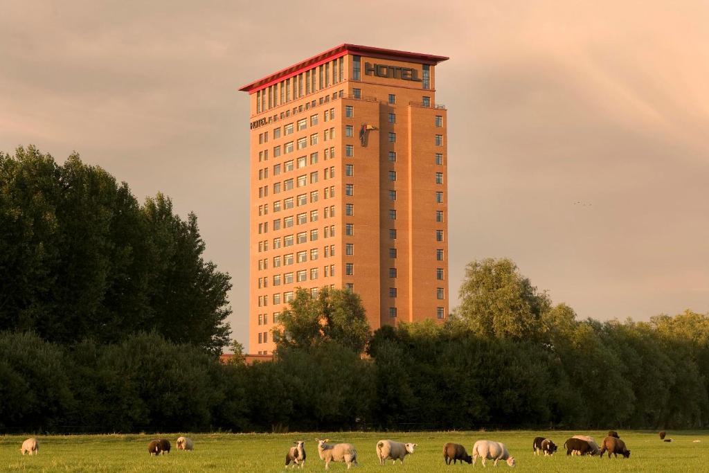 een gebouw met paarden die grazen in een veld voor een gebouw bij Van der Valk Hotel Houten Utrecht in Houten