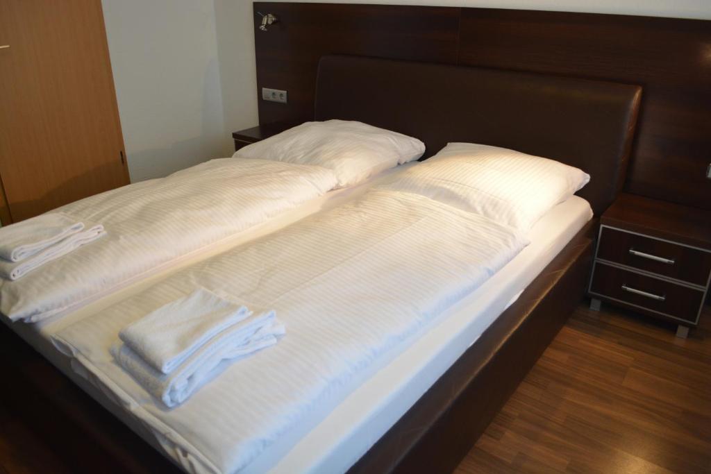 uma cama com lençóis brancos e toalhas em B&D Hotel em Hanôver