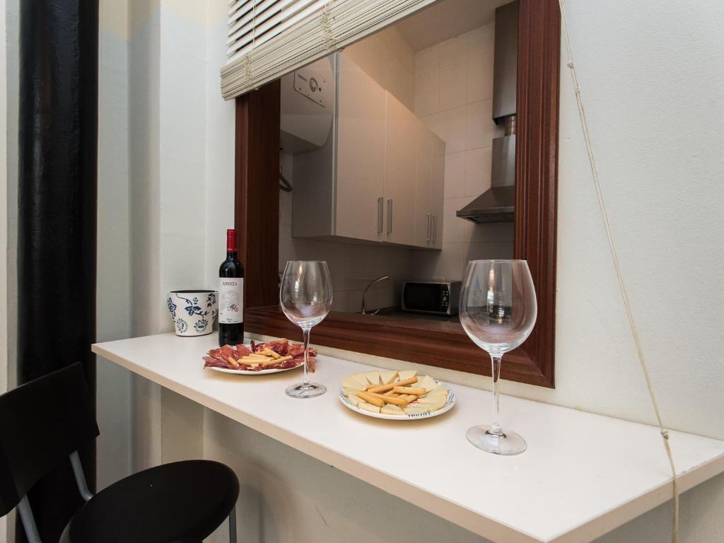 un mostrador con dos copas de vino y queso en Divi Apartments Valvanera, en Sevilla