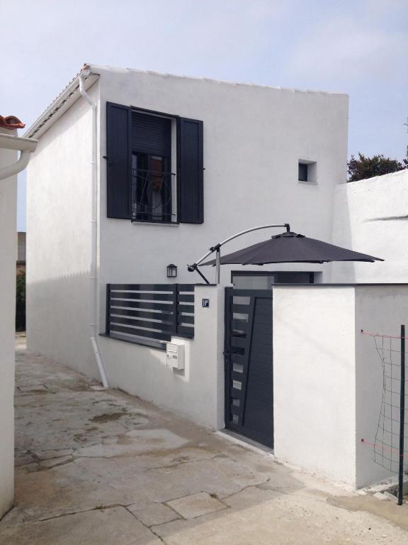 a white house with an open door and an umbrella at Oléron in Saint-Denis-dʼOléron