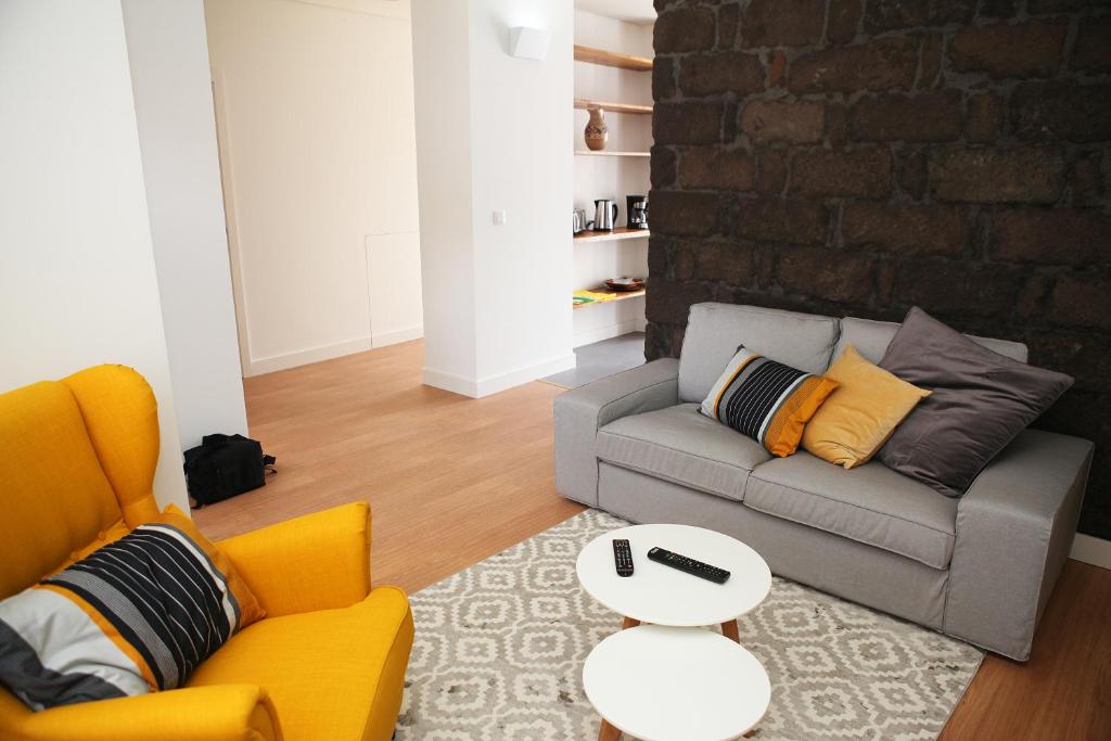 a living room with a couch and a brick wall at Casa da Cisaltina in Povoação