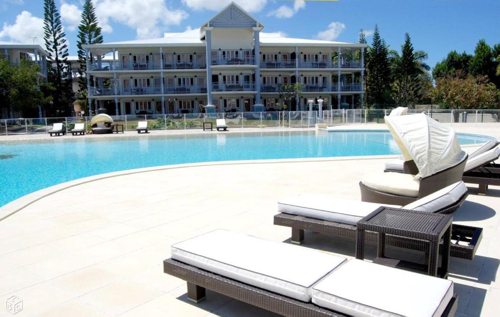 a pool with lounge chairs and a large building at Appartement à la Résidence LA PLANTATION RESORT and SPA in Saint-François