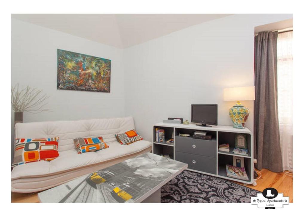 a living room with a white couch and a tv at Beco das Flores Typical Apartment in Lisbon
