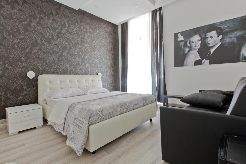 ローマにあるNew Rome house 2の白いベッドと絵付きの壁が備わるベッドルームです。