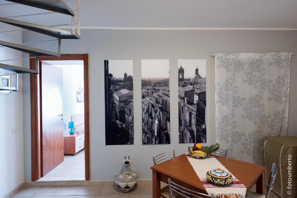 een eetkamer met een tafel en wat foto's aan de muur bij La Rosa Antica in Caltagirone