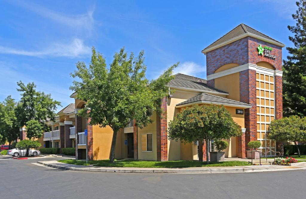 a building with a tree in front of a street at Extended Stay America Suites - Sacramento - South Natomas in Sacramento