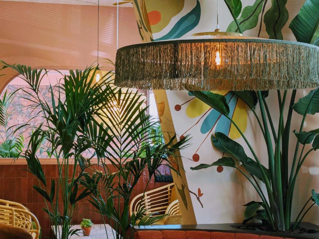 A colourful plant-filled seating corner with a large fringed pendant lamp.