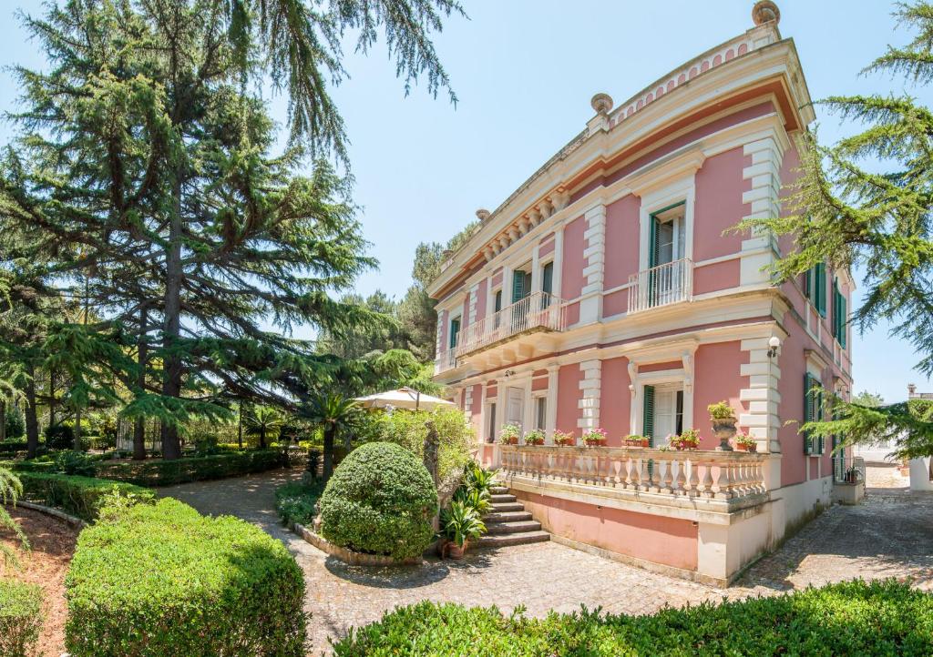 a pink house with a balcony and trees at Villa Carenza in Monopoli