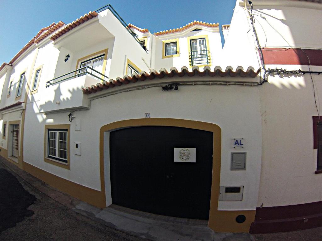 un grand bâtiment blanc avec un garage dans l'établissement Hakuna Matata Hostel, à Zambujeira do Mar